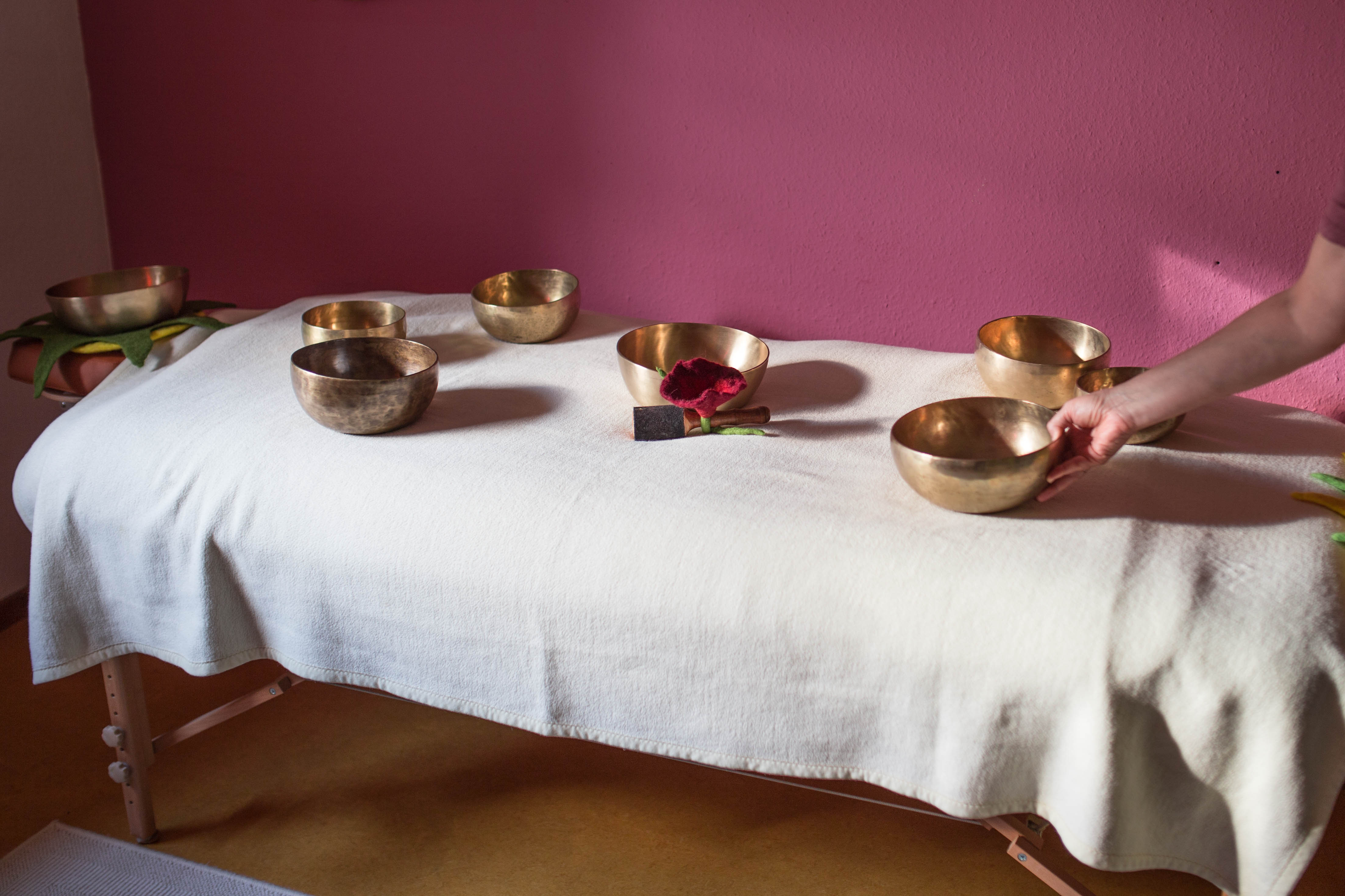 Die Massage-Liege mit Klangschalen wird für die Klangmassage vorbereitet